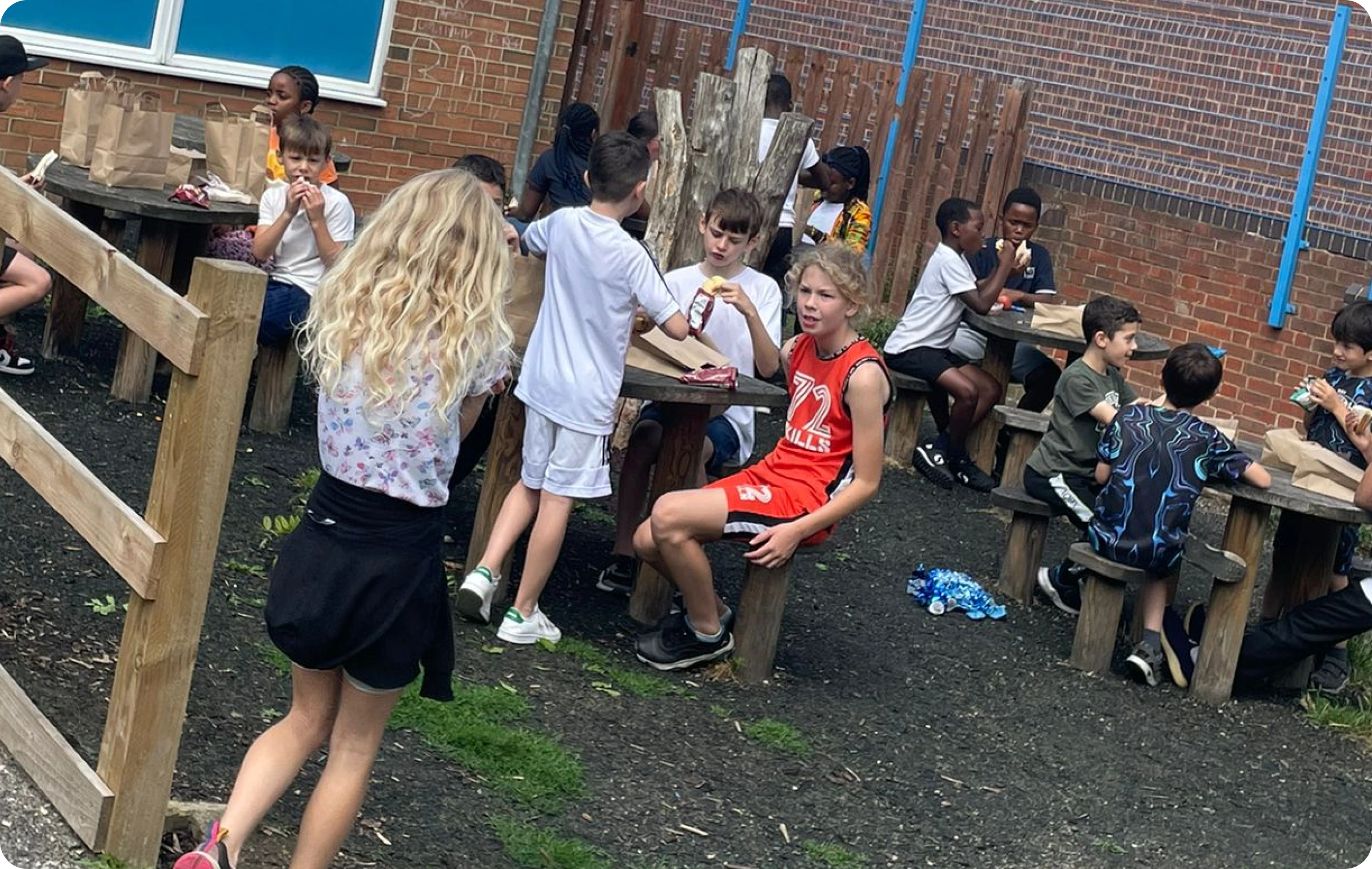 A group of children sitting together at a table, enjoying a meal and socialising during a community sports program